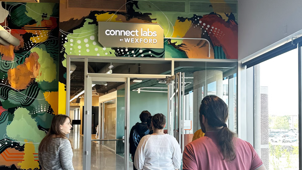 People walk through a building with a mural painted and a sign that reads Connect Labs by Wexford