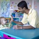 Neeraj Senthil and a toddler share a high 5 in a playroom at UC Davis Children's Hospital.