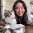 A woman holds up an organ-on-a-chip device as her cat looks on
